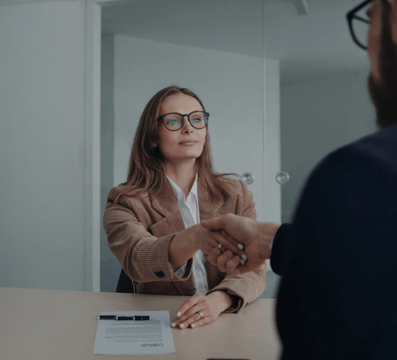 Poignée de main entre une cliente et un consultant au-dessus d’un contrat